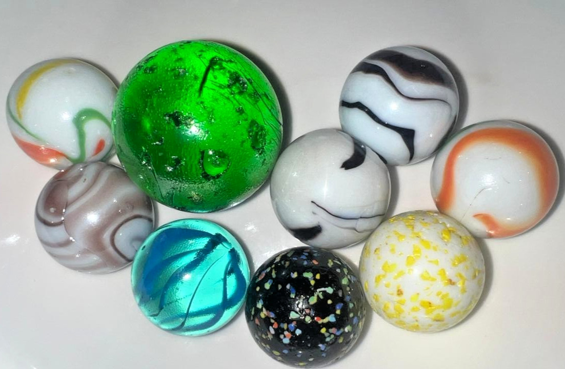 9 classic handmade glass marbles, featuring colorful swirls and unique patterns.